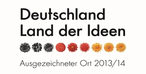 Logo „Deutschland – Land der Ideen“ mit Titel „Ausgezeichneter Ort 2013/14“ und Farbblüten.