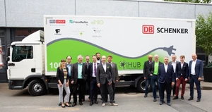 Gruppenfoto vor E-Lkw von DB Schenker mit iHub-Projektpartnern und Projektlogos auf dem Fahrzeug.